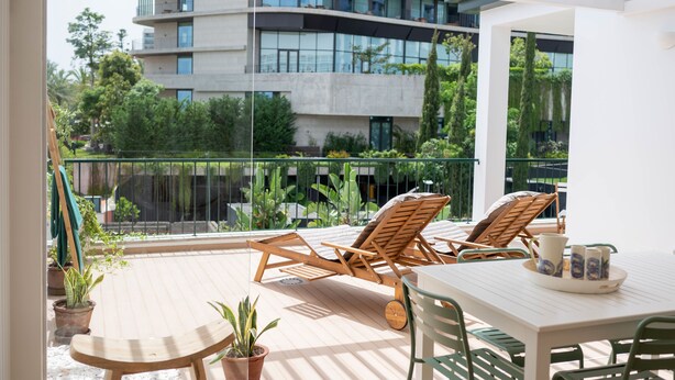 A balcony with wooden lounge chairs, a table, and potted plants. - Madeira Precious Penthouse (Funchal)