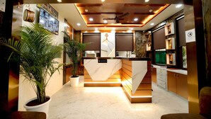 A modern reception area with a marble counter, potted plants, and a ceiling fan. - Hotel SD Prime (Jaipur)