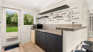 A modern kitchen with a built-in microwave, a coffee station, and a view of a garden through the door. - Hiddensee in Central Cowes (Cowes)