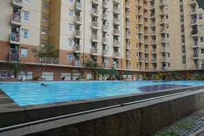 Ein Schwimmbad, umgeben von einem Hochhaus mit Balkonen.