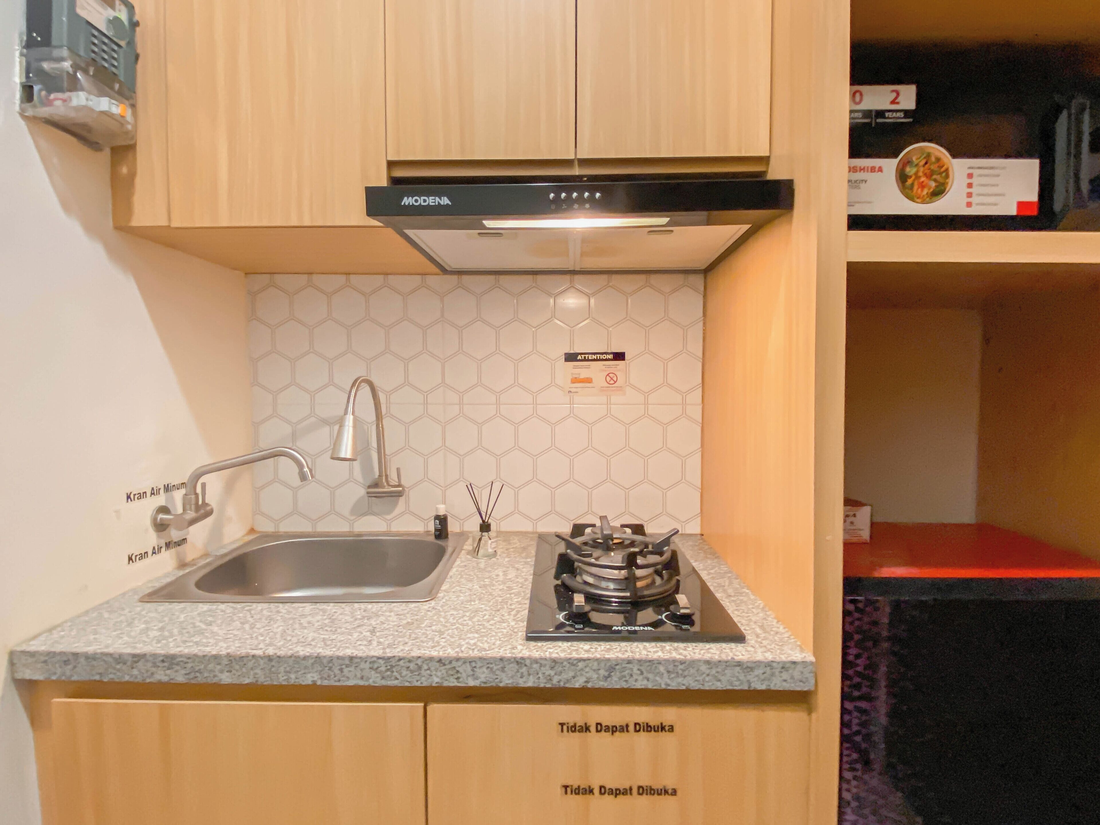 A kitchen with a stainless steel sink, a gas stove, and wooden cabinets.