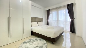 Une chambre à coucher avec un lit, une armoire, un tapis rond et une fenêtre avec des rideaux.