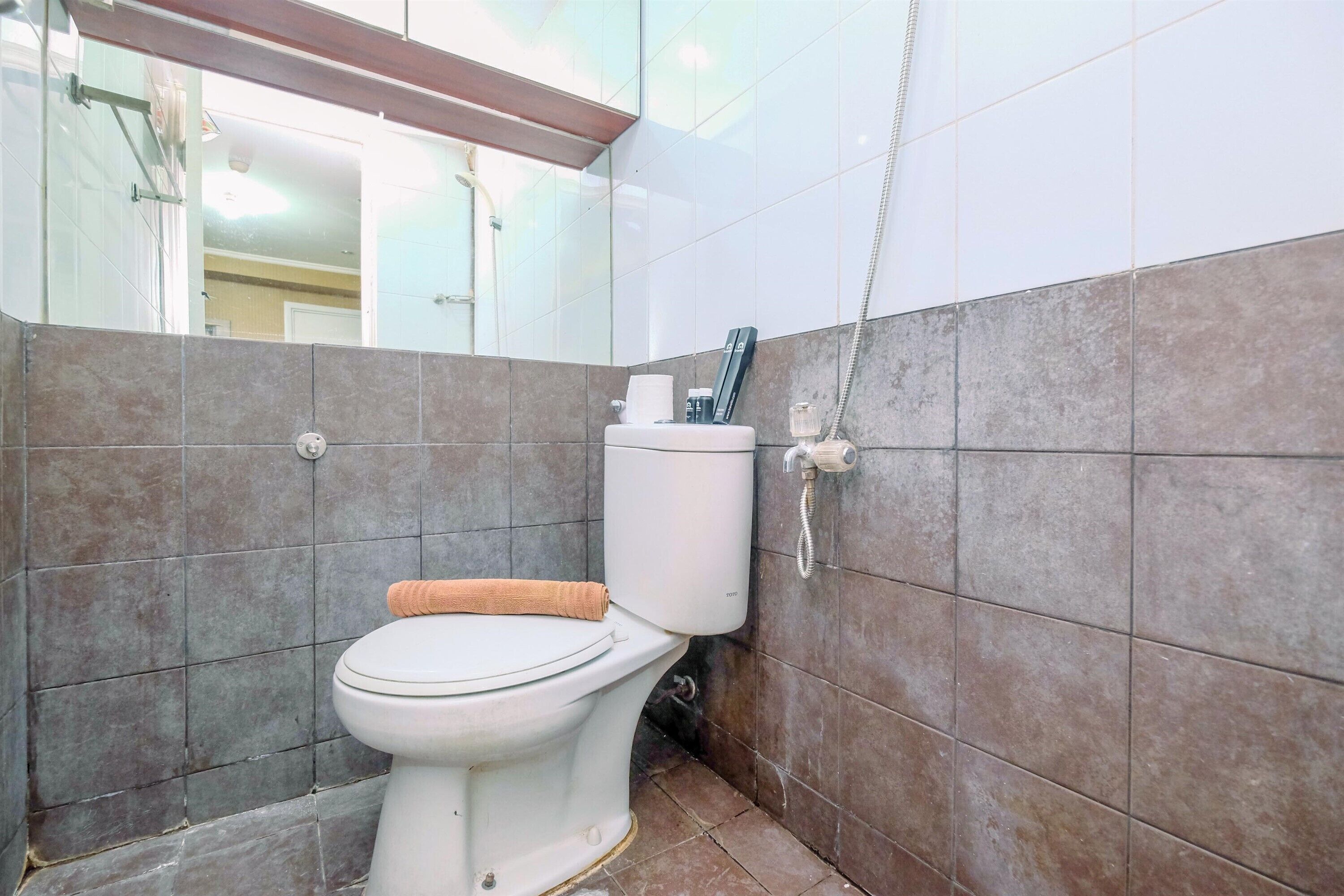 A bathroom with a toilet, a towel, and a shower head.