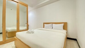 Una camera da letto con un letto in legno, biancheria bianca, uno specchio e un armadio.