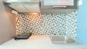 A kitchen with a gas stove, a microwave, and a sink. - Cozy Furnished Studio At Taman Melati Jatinangor Apartment (Hegarmanah)