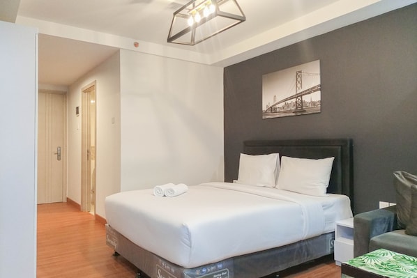 Une chambre d’hôtel avec un lit, une chaise, un bureau et un tableau accroché au mur.
