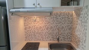 Una cucina compatta con piano cottura a induzione integrato, lavello in acciaio inossidabile e cappa aspirante Modena.