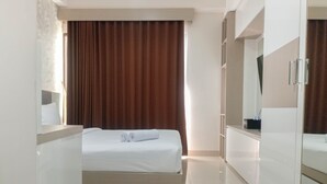 Una camera d'albergo con un letto rifatto, un grande specchio e un armadio.