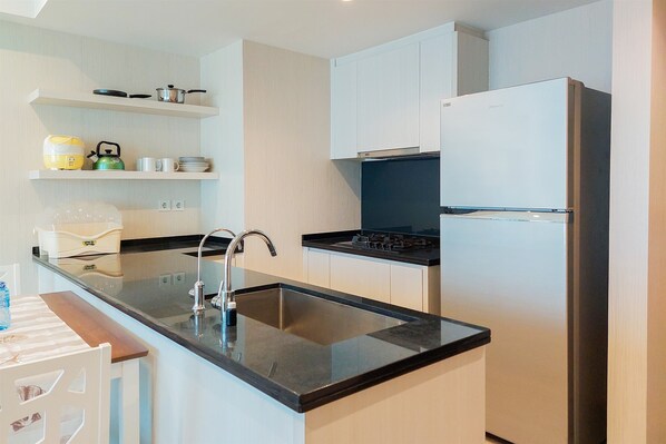 A modern kitchen with a black countertop, stainless steel sink, and white cabinets.