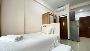 Ein Hotelzimmer mit Bett, Kleiderschrank, Kühlschrank und Klimaanlage.