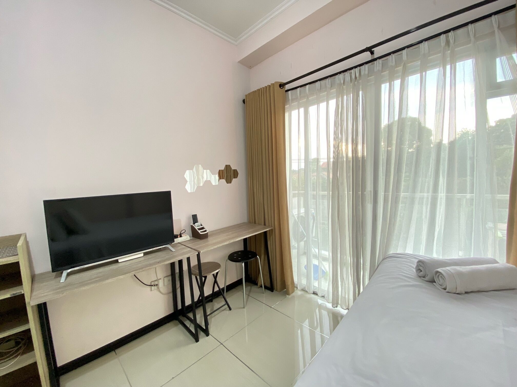 Une chambre d’hôtel comprenant un lit, une télévision, un bureau avec une chaise et une fenêtre avec des rideaux.