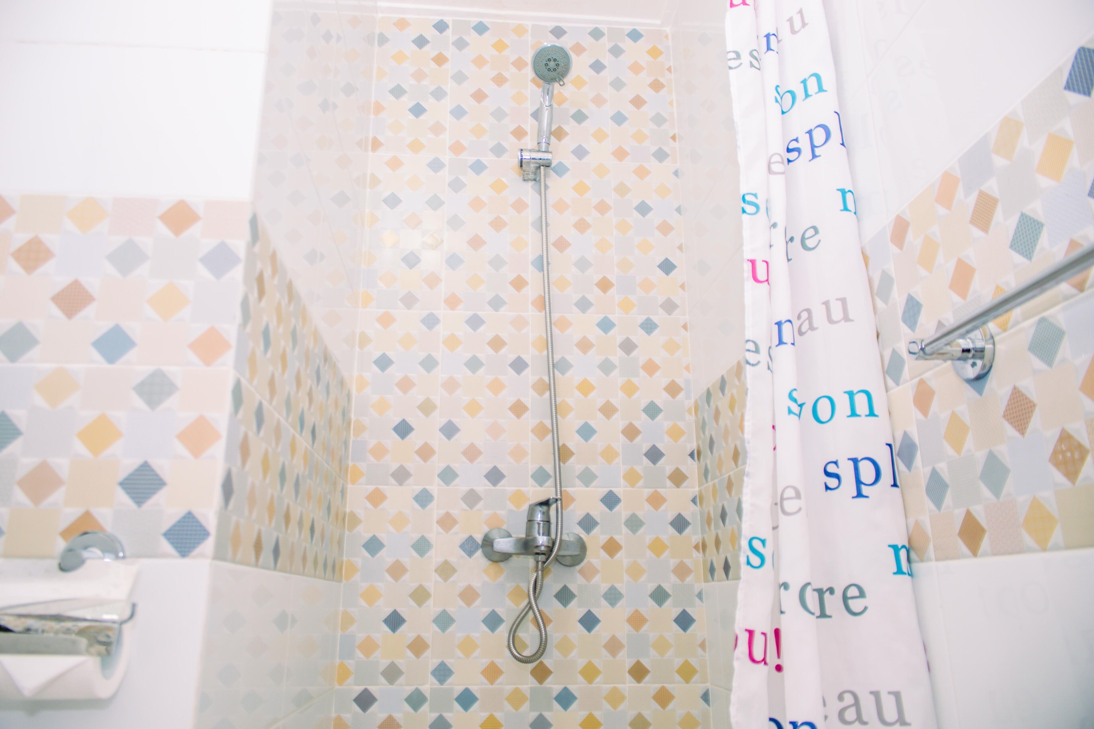 Eine Dusche mit Handbrause und Glastrennwand.
