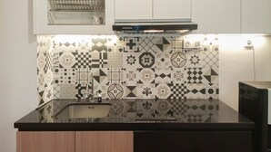 A kitchen with a black countertop, a sink, and patterned backsplash tiles. - Comfy And Easy Access 2Br Apartment At Tanglin Supermall Mansion (Surabaya)