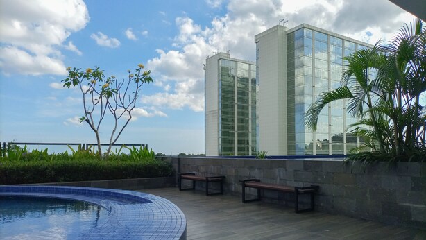 A rooftop pool area with a clear view of a modern building in the background. - Comfy And Easy Access 2Br Apartment At Tanglin Supermall Mansion (Surabaya)