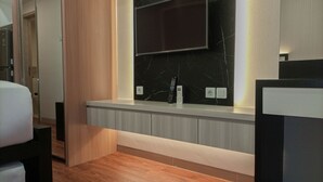 A modern hotel room with a wooden floor, a built-in bench with a TV, and a marble backsplash. - Comfy And Easy Access 2Br Apartment At Tanglin Supermall Mansion (Surabaya)
