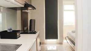 A compact hotel room with a kitchenette, a bed, and a window providing natural light. - Great Location Studio Room At Springlake Summarecon Bekasi Apartment (Bekasi)