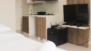 A modern hotel room with a kitchenette, a flat-screen TV, and a compact refrigerator. - Great Location Studio Room At Springlake Summarecon Bekasi Apartment (Bekasi)