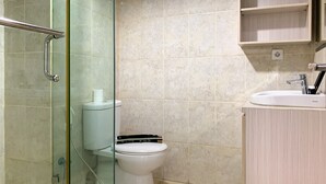 Ein Badezimmer mit Duschkabine, Toilette und Waschbecken mit Spiegel.