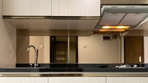 Eine moderne Küche mit einer Edelstahl-Dunstabzugshaube, einem Spülbecken mit Armatur und hellen Küchenschränken.