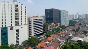 Ein Hochhaus mit mehreren Stockwerken, umgeben von kleineren Wohngebäuden mit roten Ziegeldächern.
