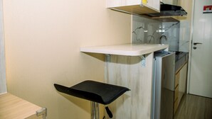 A kitchen with a white countertop, a black chair, and a refrigerator. - Simple And Cozy Studio Apartment At Urban Heights Residences (South Tangerang)