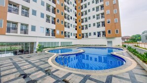 A high-rise residential building with multiple balconies and a central swimming pool area. - Simple And Cozy Studio Apartment At Urban Heights Residences (South Tangerang)