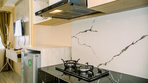 A modern kitchen with a gas stove, a built-in microwave, and a stainless steel refrigerator. - Simple And Cozy Studio Apartment At Urban Heights Residences (South Tangerang)