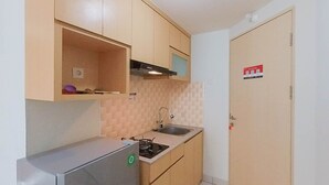 Una cocina compacta con refrigerador, pileta y muebles de madera.