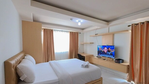 Una habitación de hotel con cama, televisor, escritorio y cortinas.