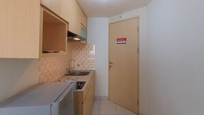 Cocina compacta con muebles de madera, un lavamanos y una puerta con un cartel de seguridad contra incendios.