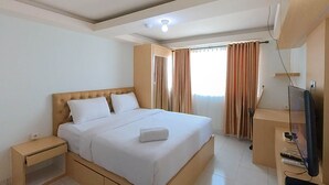 Habitación de hotel con una cama grande, una mesita de noche, un televisor y una ventana con cortinas.