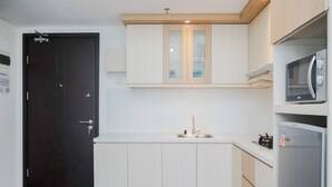A modern kitchen with white cabinets, a black door, and a built-in microwave. - Minimalist Spacious Studio Room At Apartment Galeri Ciumbuleuit 1 (Bandung)