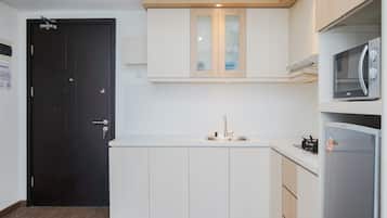 Una cocina moderna con armarios blancos, una puerta negra y un microondas integrado.