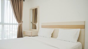 A hotel room with a bed, a bedside table, a mirror, and a window with curtains. - Minimalist Spacious Studio Room At Apartment Galeri Ciumbuleuit 1 (Bandung)