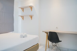 A modern hotel room with a bed, two wooden shelves, a desk, and a chair. - Comfort And Simple 1Br At Casa De Parco Apartment (South Tangerang)