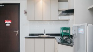 A compact kitchen with a sink, gas stove, and cabinets. - Comfort And Simple 1Br At Casa De Parco Apartment (South Tangerang)