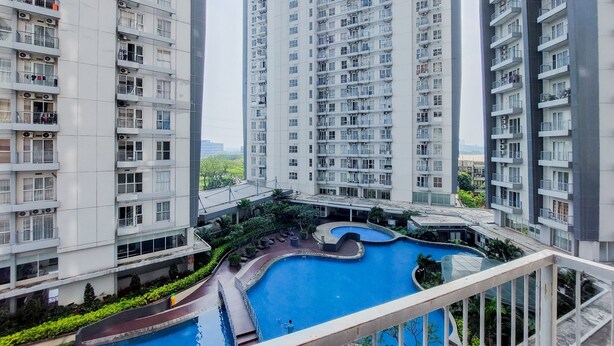 A high-rise residential building with multiple balconies and a swimming pool area. - Comfort And Simple 1Br At Casa De Parco Apartment (South Tangerang)