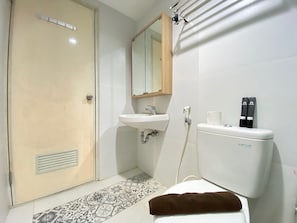 A compact bathroom with a wall-mounted sink, toilet, and mirror.