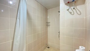Um banheiro pequeno e revestido com azulejos, com chuveiro, vaso sanitário e porta-toalhas.