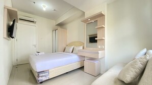 Quarto moderno com cama, armário embutido, espelho e televisão.