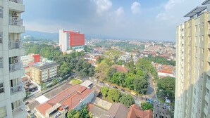 Um edifício alto com várias varandas, situado numa área urbana densamente povoada, com diversos edifícios e vegetação.