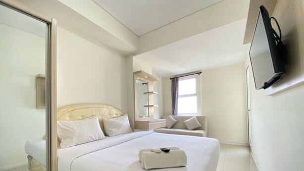 Quarto de hotel com uma cama, televisão, espelho, janela e banheiro.
