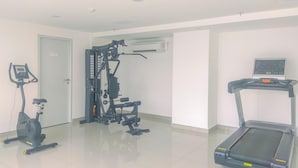 A gym with a stationary bike, a multi-functional exercise machine, and a treadmill. - Fancy And Nice Studio Apartment At Sayana Bekasi (Bekasi)