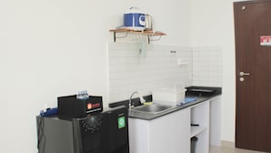 A compact kitchen with a sink, a coffee maker, and a small refrigerator. - Fancy And Nice Studio Apartment At Sayana Bekasi (Bekasi)