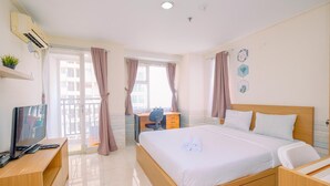 A hotel room with a bed, a desk, a TV, and a balcony with curtains. - Fully Furnished And Comfy Studio Apartment Margonda Residence 3 (Depok)