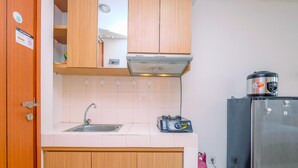 A compact kitchen with a sink, a toaster, and a refrigerator. - Fully Furnished And Comfy Studio Apartment Margonda Residence 3 (Depok)