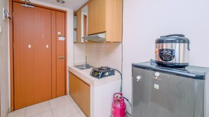 A compact kitchen with a gas stove, a refrigerator, and a gas cylinder. - Fully Furnished And Comfy Studio Apartment Margonda Residence 3 (Depok)
