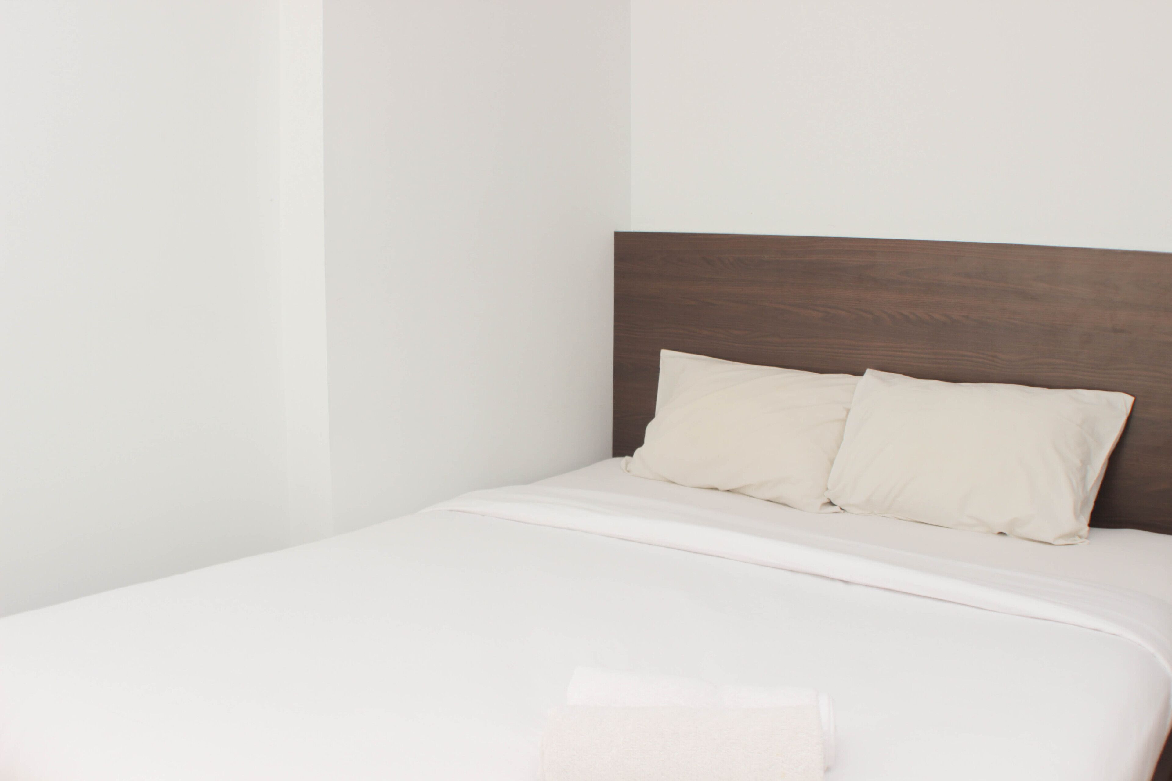 A bed with a wooden headboard and two pillows.