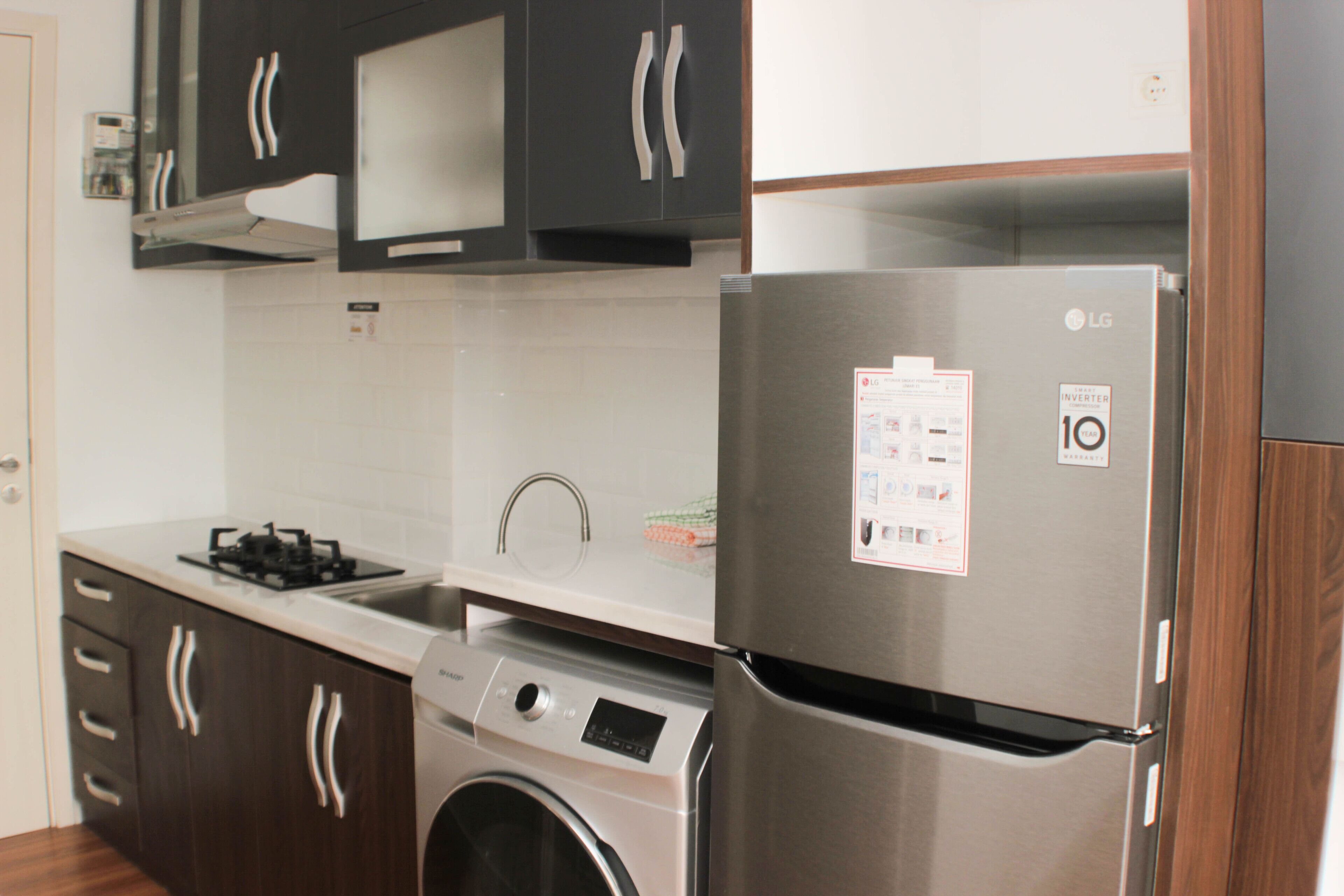 Une cuisine moderne équipée d’appareils électroménagers en acier inoxydable, notamment un réfrigérateur, un lave-linge et une cuisinière.