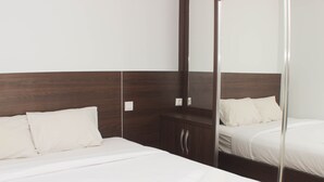 Ein Hotelzimmer mit einem großen Bett, einem hölzernen Kopfteil, einem Spiegel und einem Kleiderschrank.